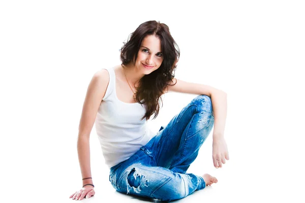 Mujer bonita en pantalones vaqueros azules sentado en el suelo blanco — Foto de Stock