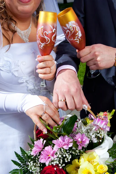 Mãos de noiva e noivo com buquê e taças de champanhe — Fotografia de Stock
