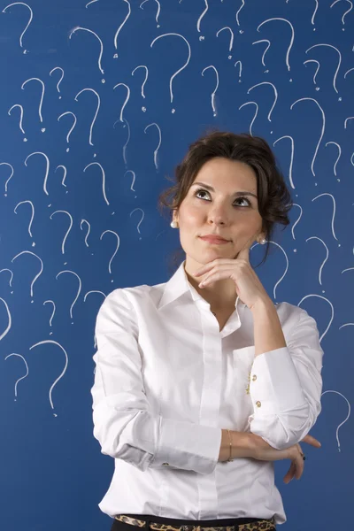 Thinking business woman in front of question marks written blackboard — Stock Photo, Image