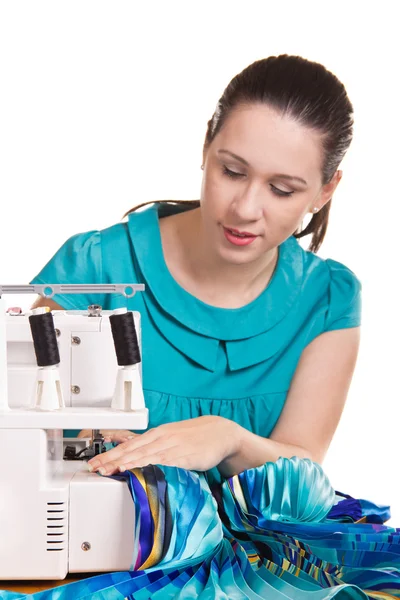 Девушка в синем платье на швейной машинке штопать — стоковое фото