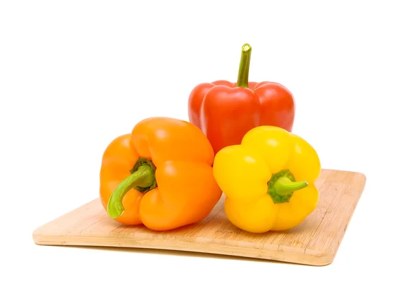 Paprika's van verschillende kleuren op een snijplank — Stockfoto