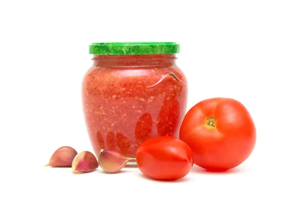 Pomidory, czosnek i kaukaski sos Adżyka w szklanym słoju na — Zdjęcie stockowe
