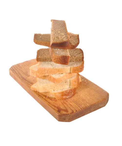 Pieces of bread lay on a wooden board — Stock Photo, Image