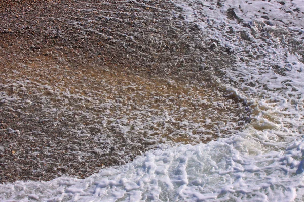 Ola y espuma en una playa de guijarros en Etretat —  Fotos de Stock
