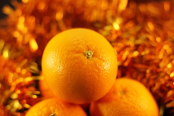 Pomarańczowy z bliska na tle migoczących girlandy — Zdjęcie stockowe