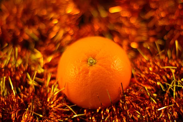 Orange close up on a background of twinkling garlands — Stock Photo, Image