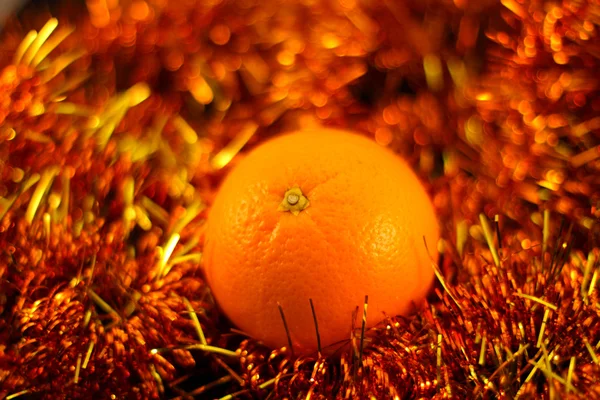 Oranžová zblízka na pozadí třpytící girlandy — Stock fotografie