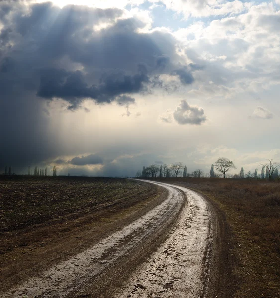 Dramatic sky over field with dirty road — Stock Photo, Image