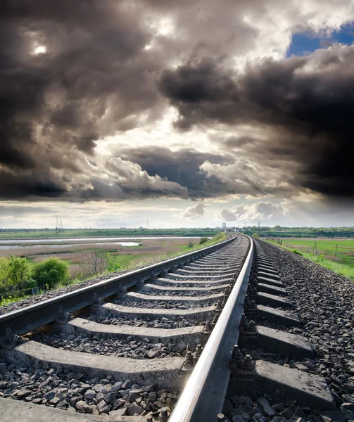 Blick auf die Eisenbahn geht zum Horizont unter wolkenverhangenem Himmel mit Sonne — Stockfoto