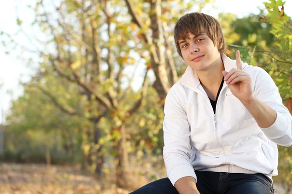 Dikkat! yakışıklı adam sonbahar parktaki bankta oturmuş — Stok fotoğraf
