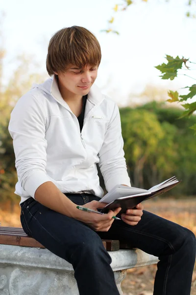 Young relaxed man reading book in nature, autumn Royalty Free Stock Images