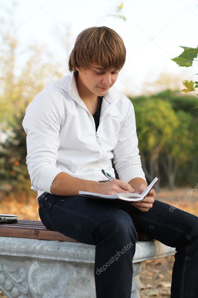 Young man write poetry, autumn outdoors