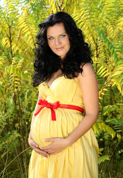 Mooie zwangere vrouw met rode band op buik, buitenshuis — Stockfoto