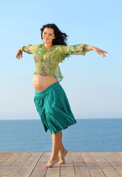 Vliegende gelukkig zwangere vrouw op zee achtergrond — Stockfoto