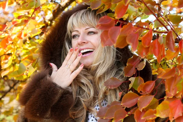 Glücklich lächelnde Frau, die im Herbst draußen spazieren geht — Stockfoto