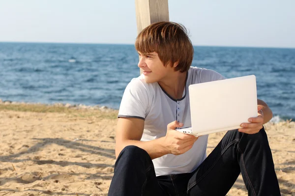 Улыбающийся мужчина с ноутбуком на открытом воздухе на пляже, на открытом воздухе — стоковое фото