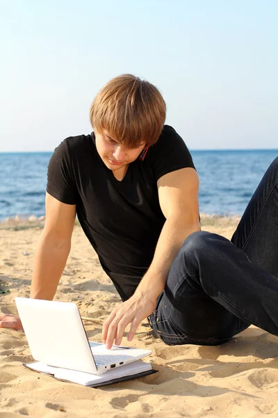 商业年轻小伙子在海滩的笔记本电脑在工作 — 图库照片