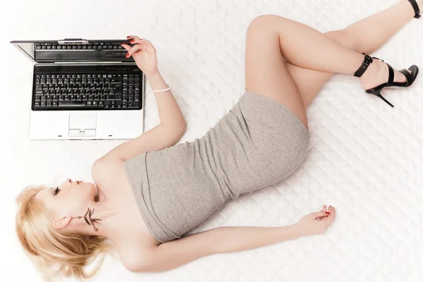 Jovem menina loira atraente deitado com notebook — Fotografia de Stock
