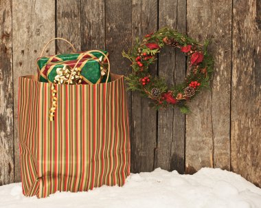 Wreath and bag with Christmas gifts on snow. clipart