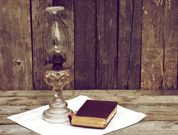 Lámpara de aceite antigua y libro sobre madera . — Foto de Stock