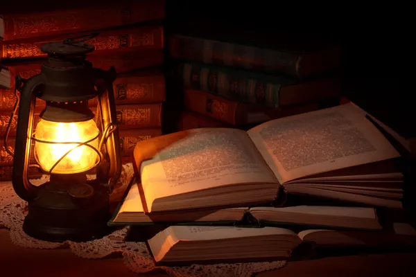 Старая масляная лампа и старые книги — стоковое фото
