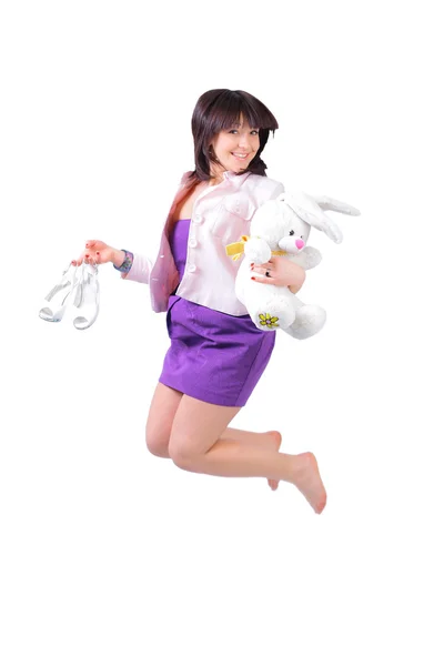 Молода красива жінка стрибає в радості з плюшевим кроликом і білим взуттям — стокове фото