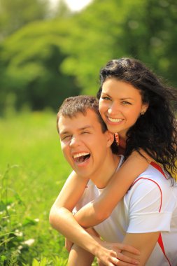 Happy young couple enjoying backriding outdoors clipart