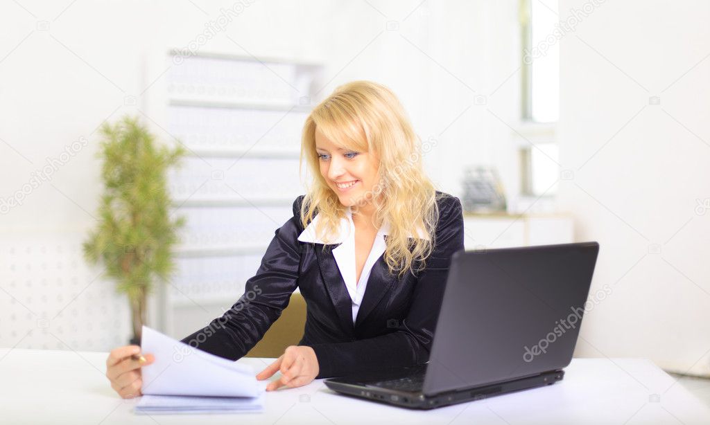 Smiling young business woman using laptop at work in an office