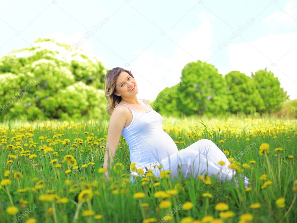 Pregnant woman sitting on meadow