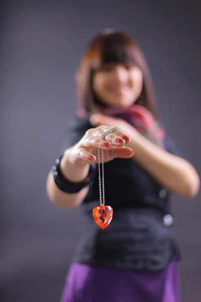 Young beautiful woman holding heart, isolated on dark background — Stock Photo, Image