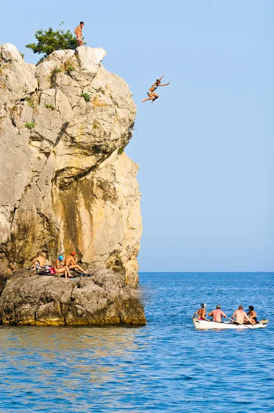 Чоловік стрибає зі скелі з глибоким блакитним морем — стокове фото