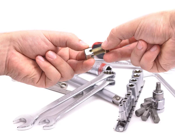 Hand with a nut and bolt on the background of wrenches — Stock Photo, Image