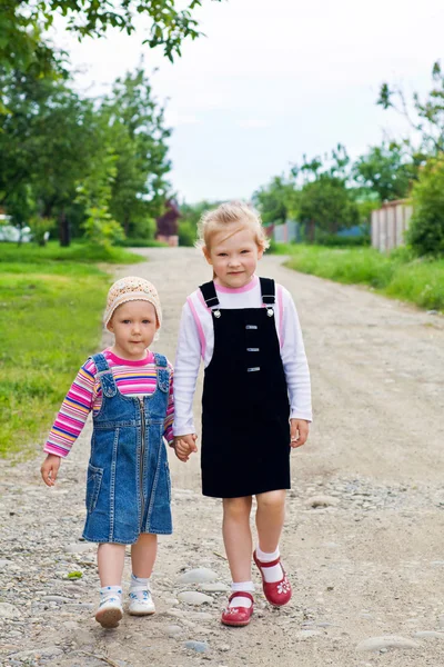 Duas meninas pequenas está andando em uma estrada — Fotografia de Stock
