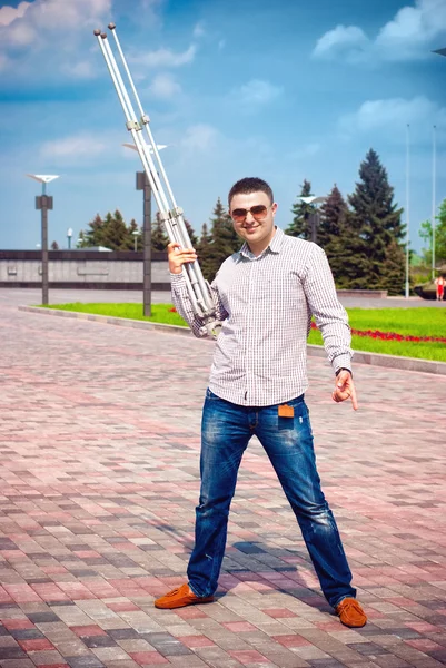 Man having fun and holding a tripod from the camera — Stock Photo, Image