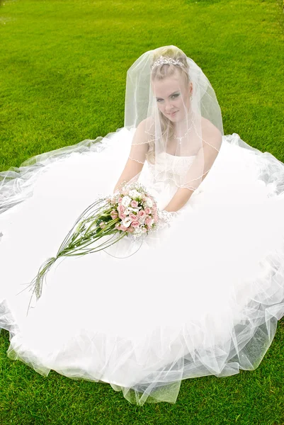 Прекрасная невеста позирует в день своей свадьбы на траве — стоковое фото