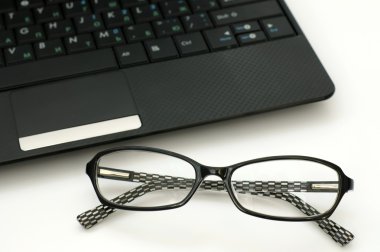 Business glasses near a laptop keyboard