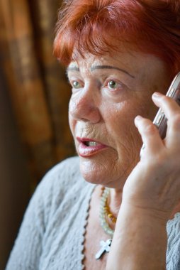 Frightened senior woman with cellphone clipart