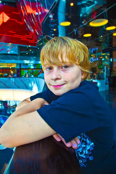 Boy resting at a balustrade in a modern shopping center — Stock Photo, Image