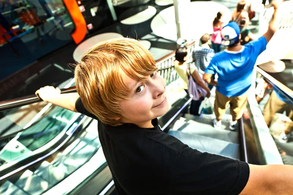 Boy on a moving staircase in the shopping center — Stock Photo, Image