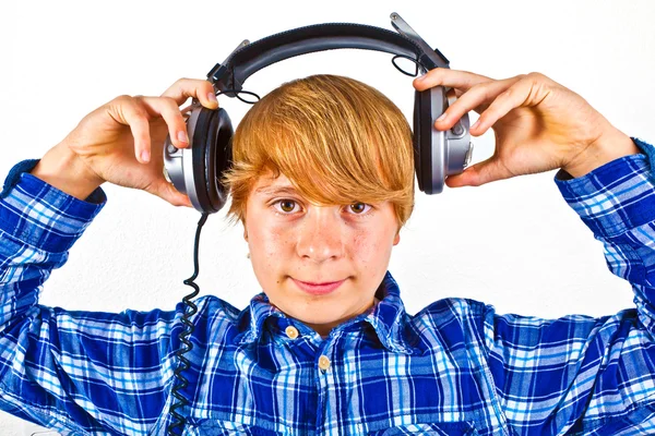 Rapaz feliz com fones de ouvido ouve música — Fotografia de Stock