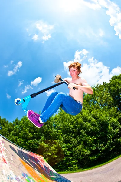 Ung pojke kommer luften med en skoter — Stockfoto