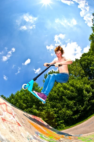 Мальчик летит по воздуху на скутере — стоковое фото