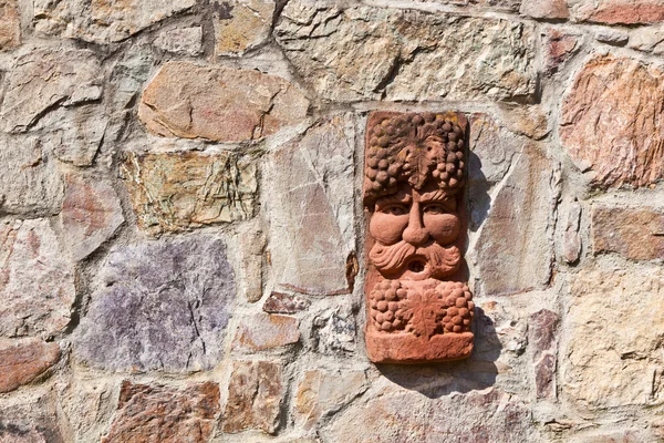 Oude middeleeuwse stenen muur met gezicht van baccus, de god van winery — Stockfoto