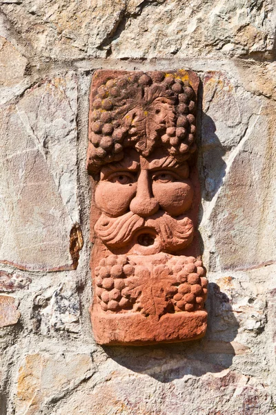 Oude middeleeuwse stenen muur met gezicht van baccus, de god van winery — Stockfoto