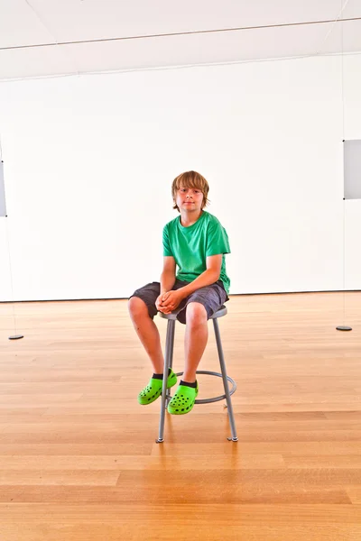 Menino feliz relaxando em uma cadeira no museu — Fotografia de Stock
