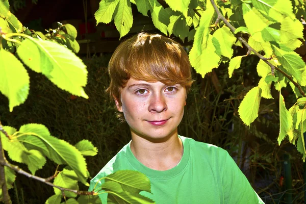 Χαριτωμένο έξυπνο αγόρι στον κήπο κάτω από το δέντρο — Φωτογραφία Αρχείου
