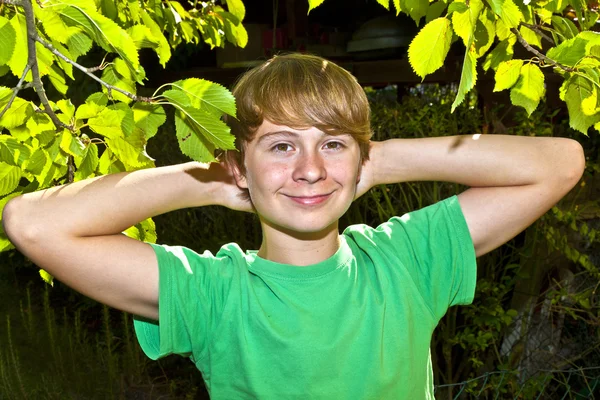 Χαριτωμένο έξυπνο αγόρι στον κήπο κάτω από το δέντρο — Φωτογραφία Αρχείου