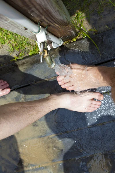 Father ans son are cleaning the feet with water at the beach — Stock Photo, Image