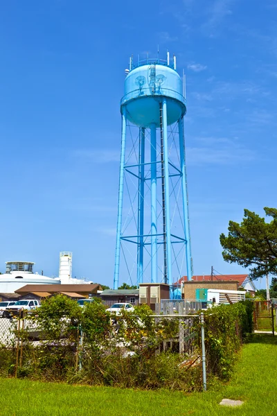 Uma torre de água azul contra um céu azul nublado — Fotografia de Stock