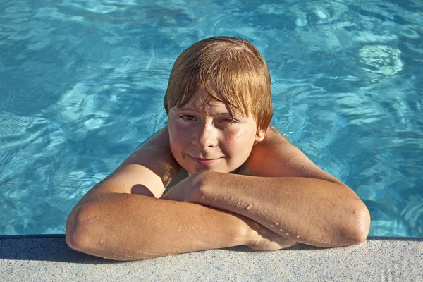 Kind rest op zijn elleboog op de rand van het zwembad — Stockfoto